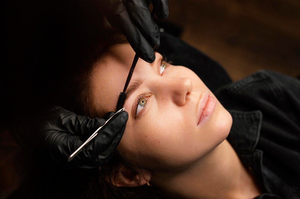 high-angle-female-clinician-doing-eyebrow-treatment-female-customer